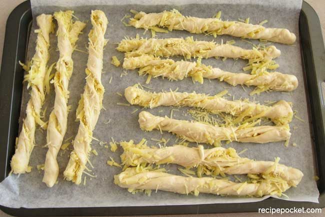 Homemade cheese bread sticks on baking tray.