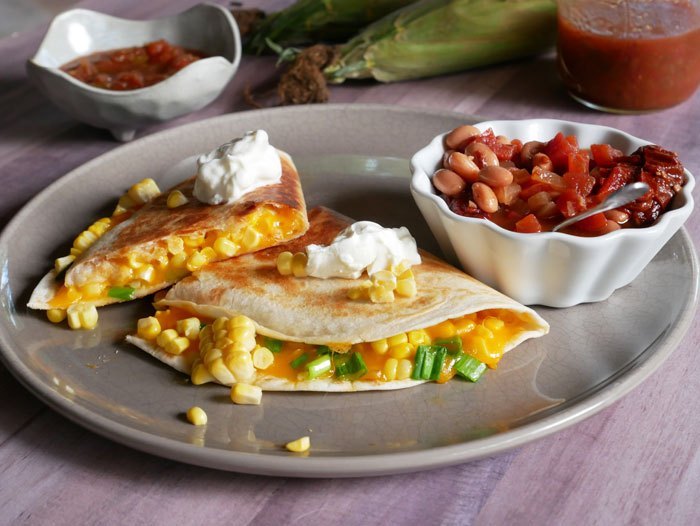 Corn quesadillas with salsa in the back ground.