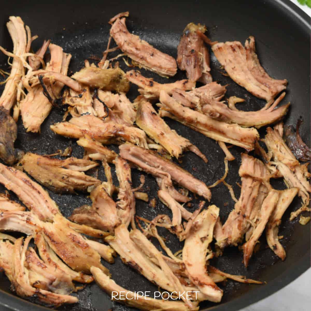 Fried shredded pork meat in a black skillet.