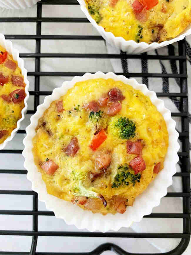 A top view of prosciutto and egg muffs in white muffin cases.