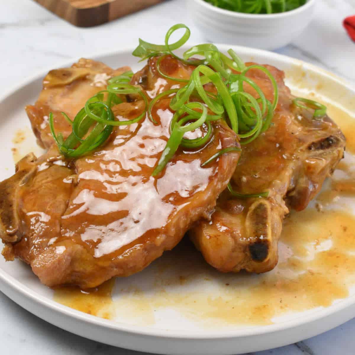 Pork chops in gravy with spring onion curls.