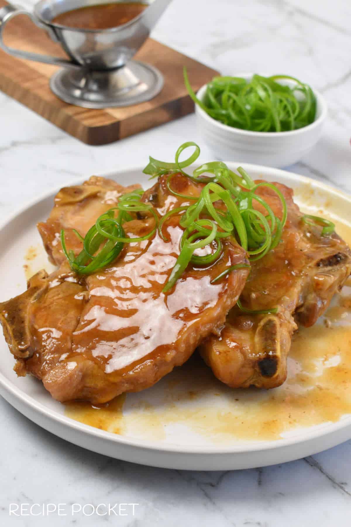 Pork chops garnished with spring onion curls.