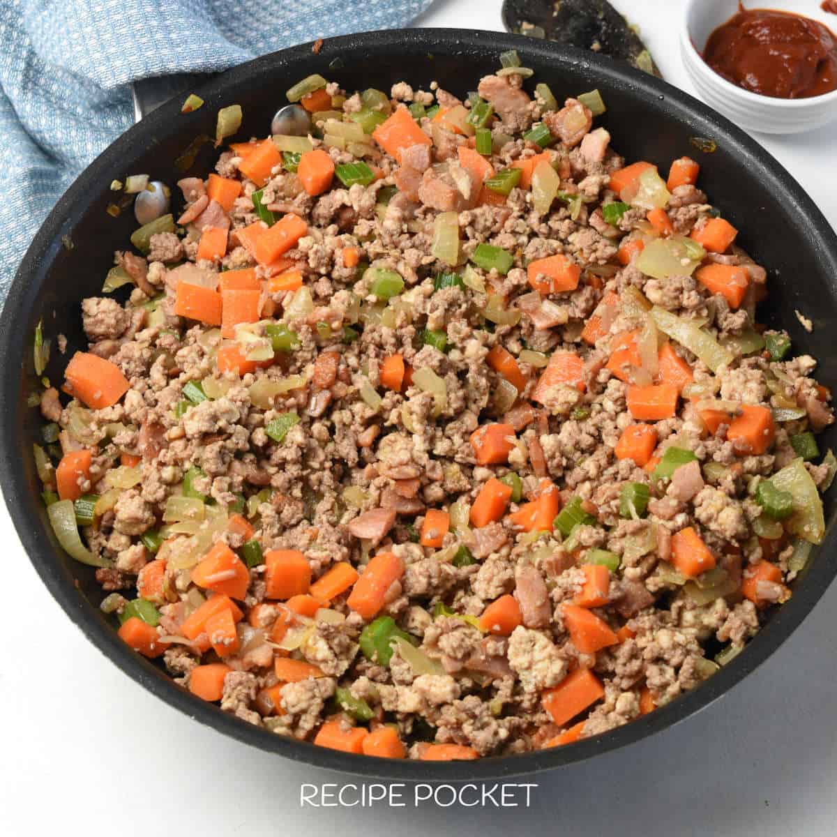 Sauteed vegetables and ground beef and pork in a skillet.