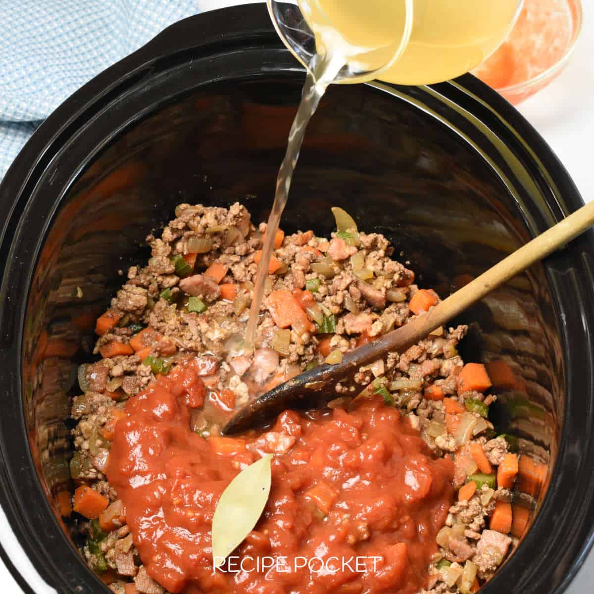 Stock being poured over ingredients in a slow cooker.