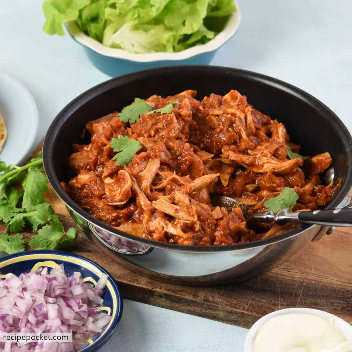 Chicken tinga in a skillet garnished with fresh herbs.