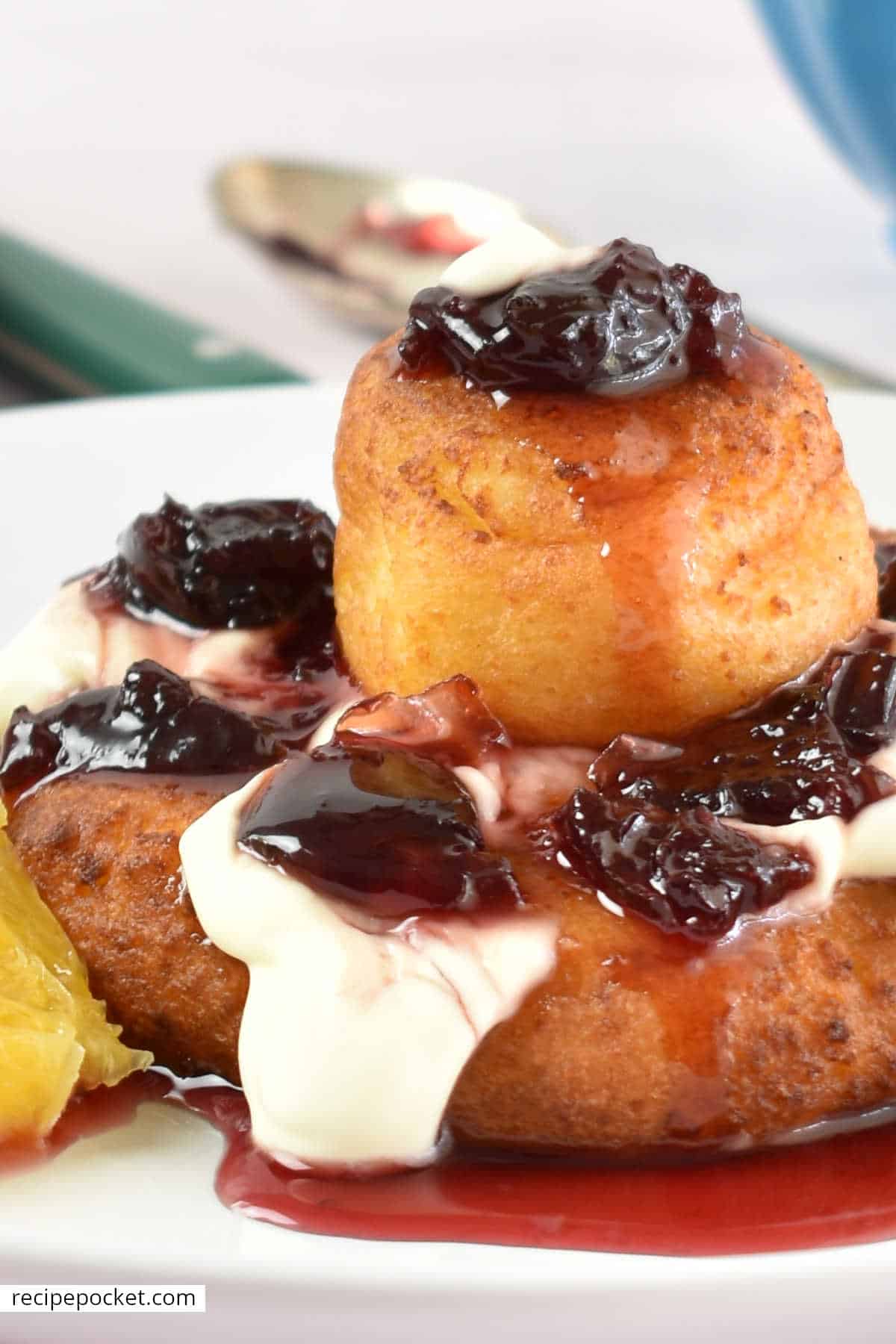 A closeup of papanasi with sour cream and cherry jam.