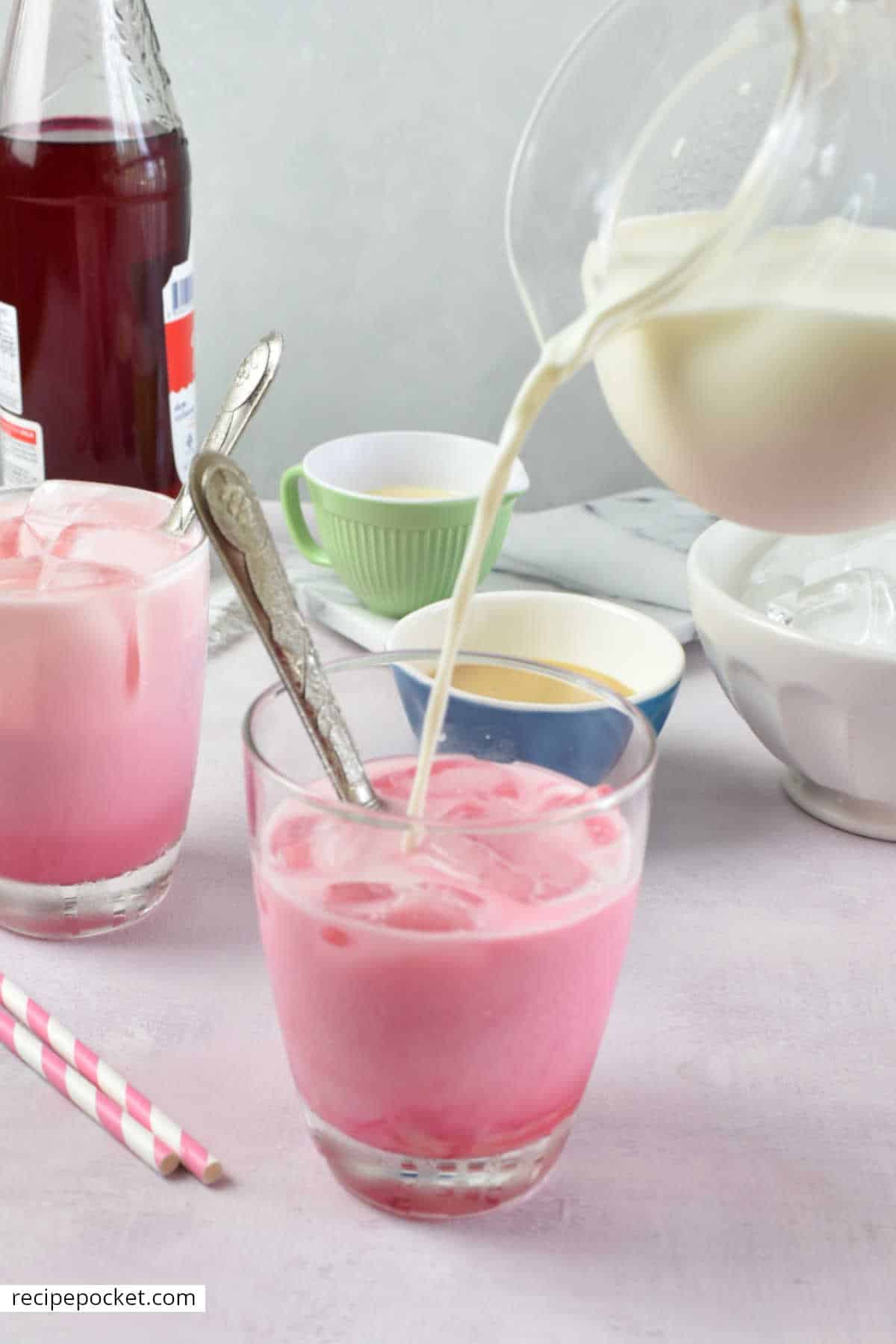Milk being poured into a glass with ice and sala syrup.