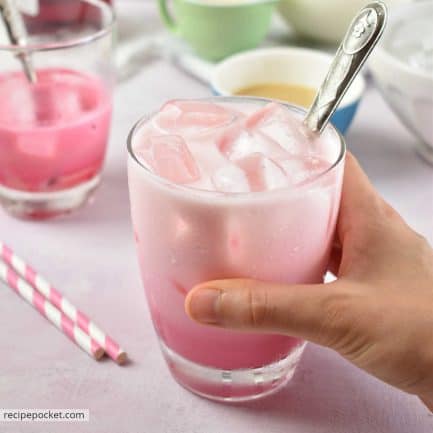 A picture of a hand holding a glass of Thai pink milk.