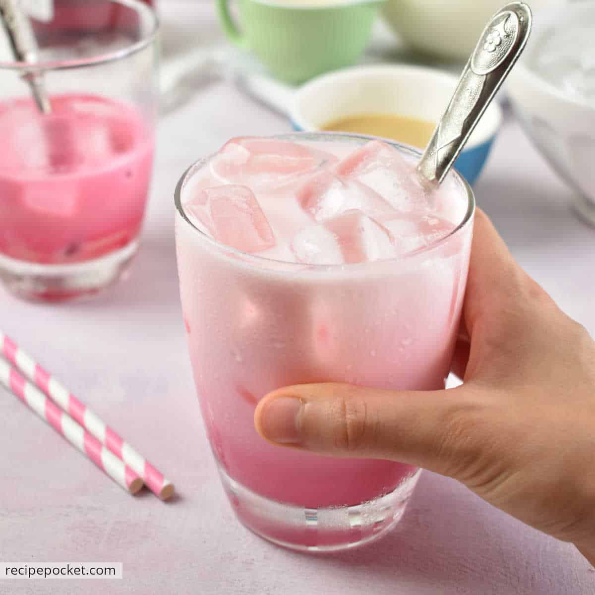 A picture of a hand holding a glass of Thai pink milk.