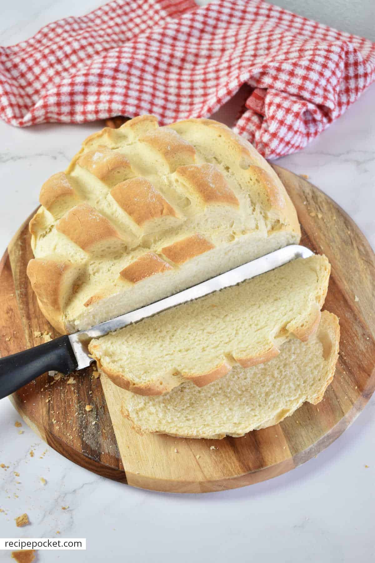 Sliced cob bread on a cutting board with a red cloth in the background.
