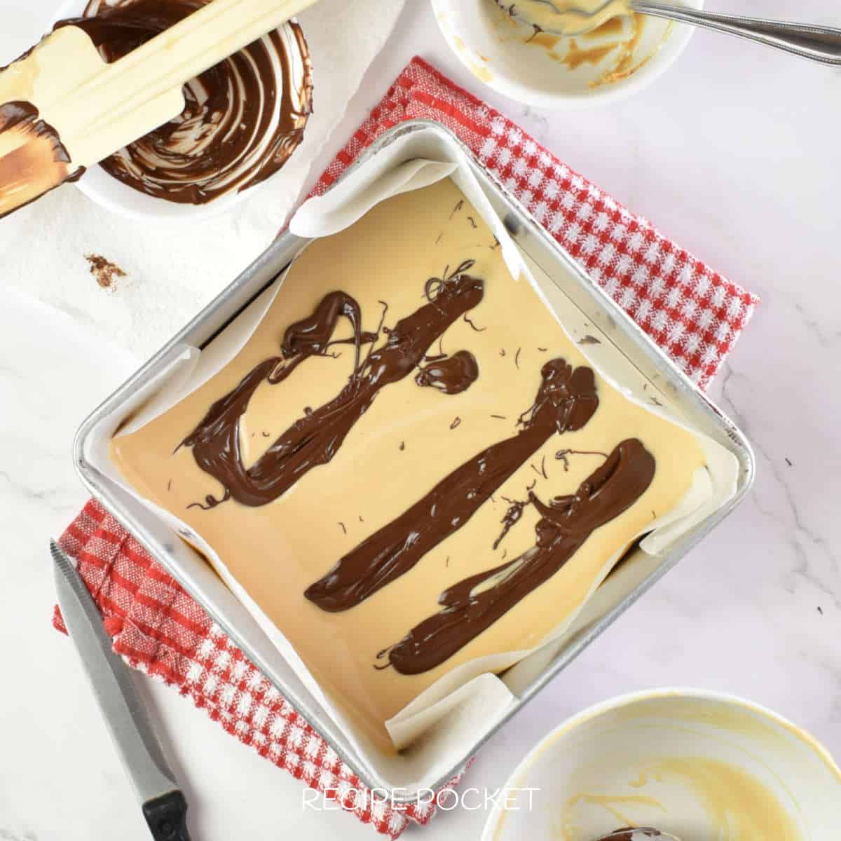 Stripes of melted dark chocolate on an unset fudge mixture.