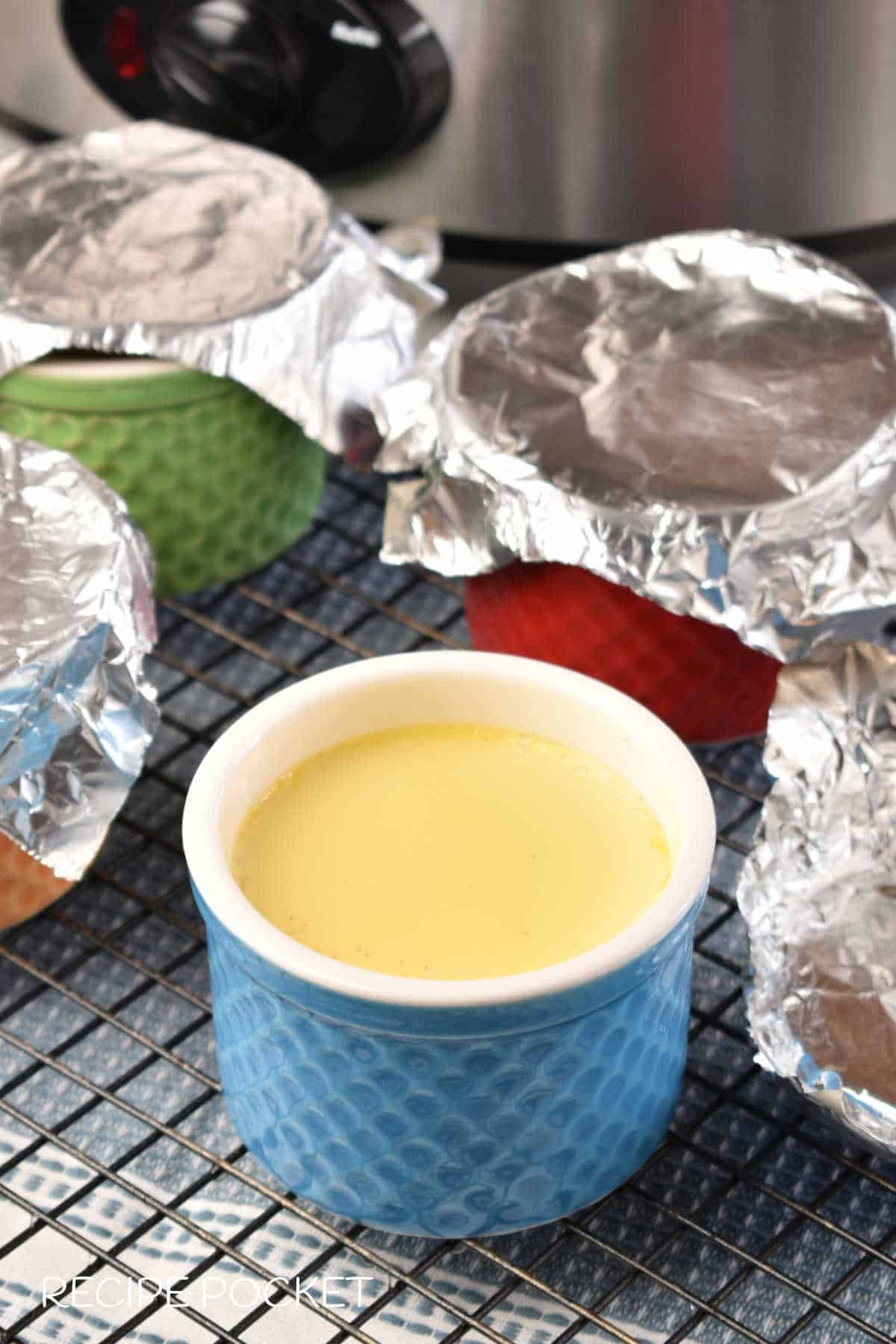 Cooked egg custard in small pots on a cooling rack.
