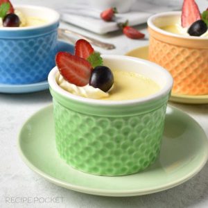 Three ramekins filled with slow cooker egg custard and garnished with strawberries and cream.