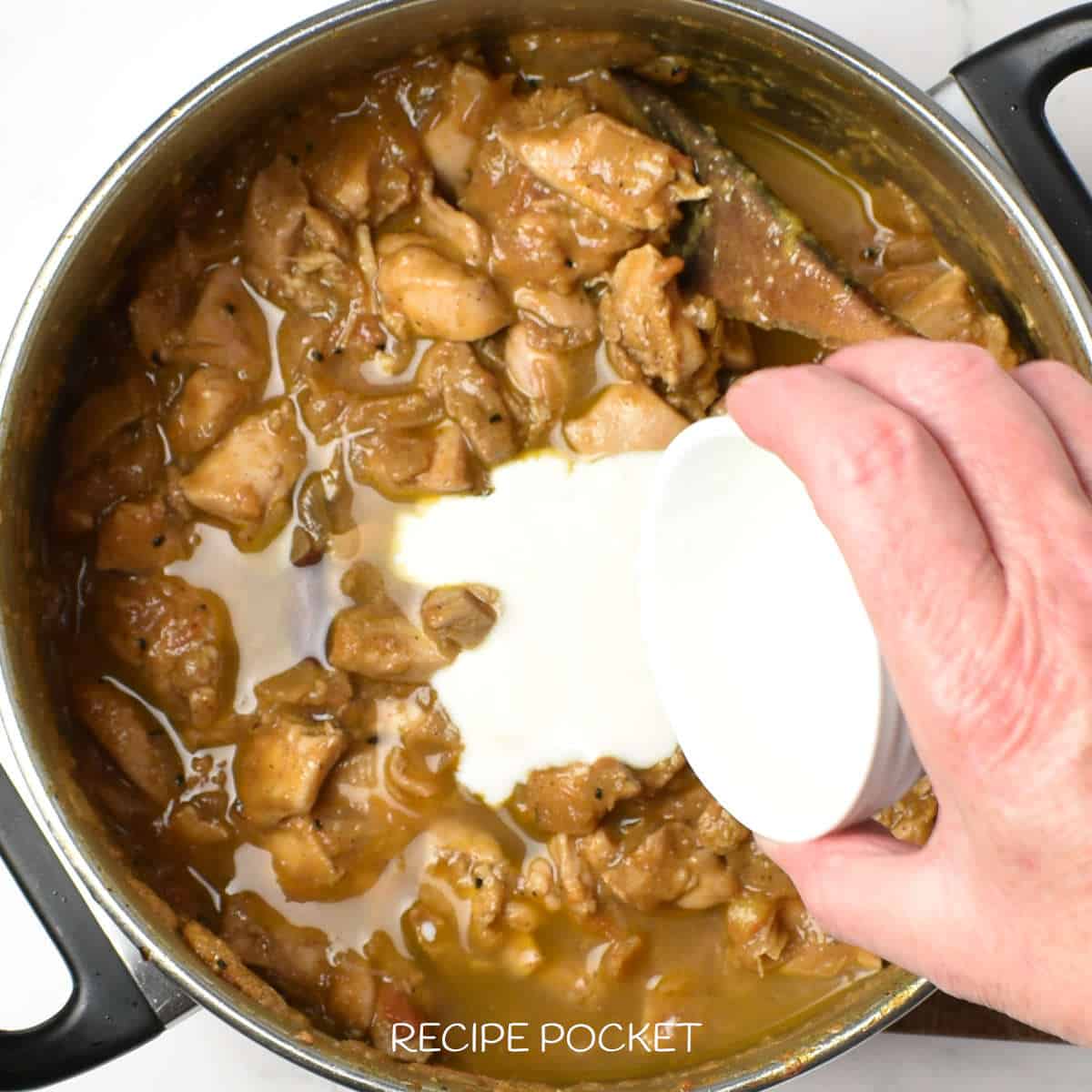 Yogurt being added to balti chicken.