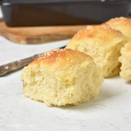 Close up of a dinner rolls on a white table with more rolls at the back.