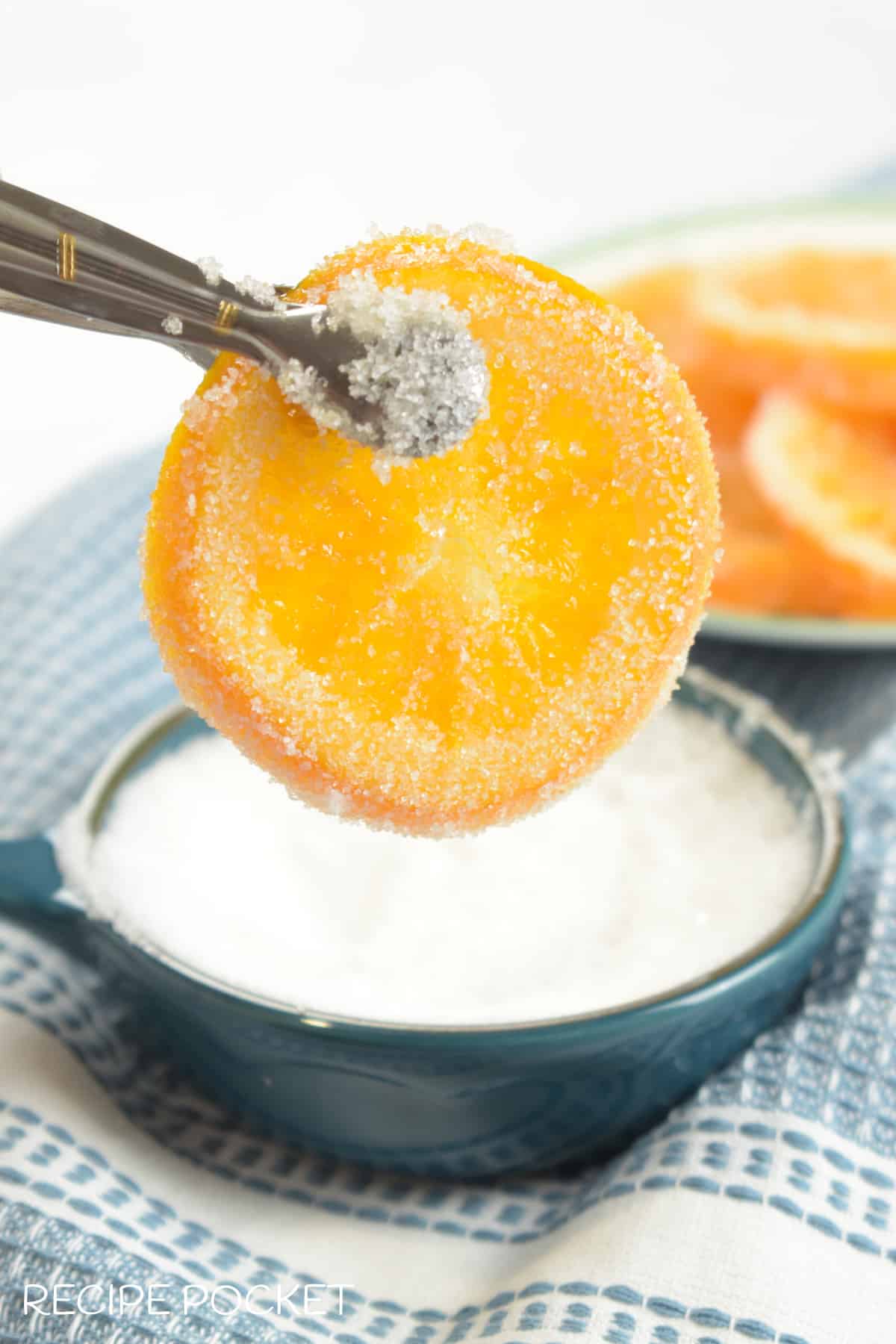 Image showing and candied orange slice being dipped in sugar.