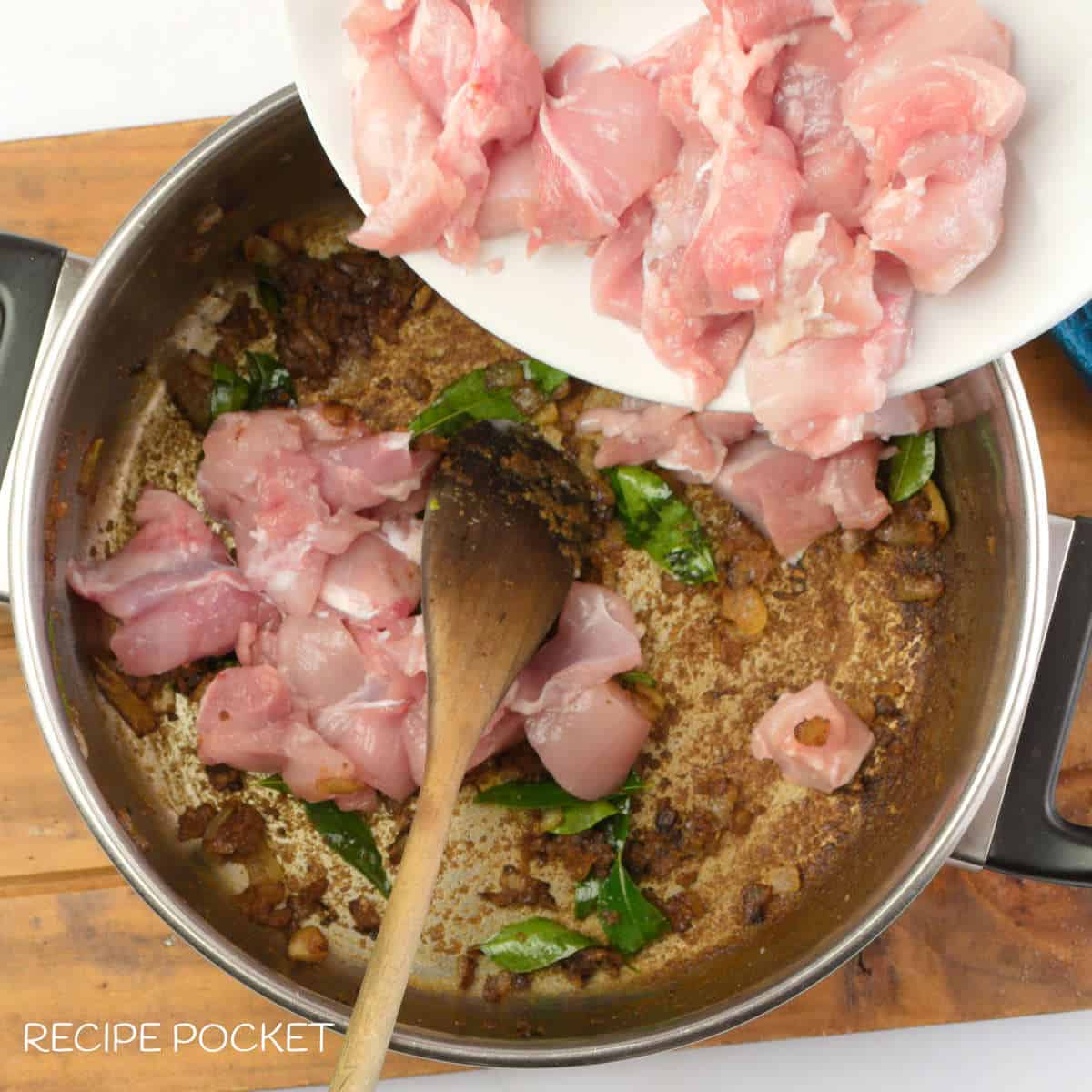Chicken meat being added to a pot.