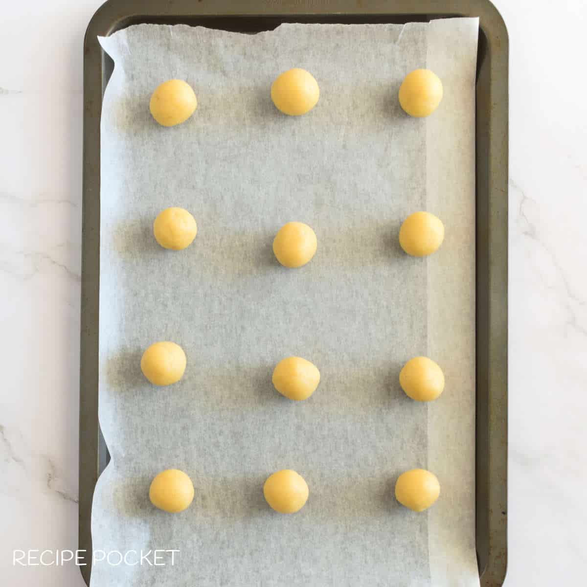 Balls of cookie dough on a tray.