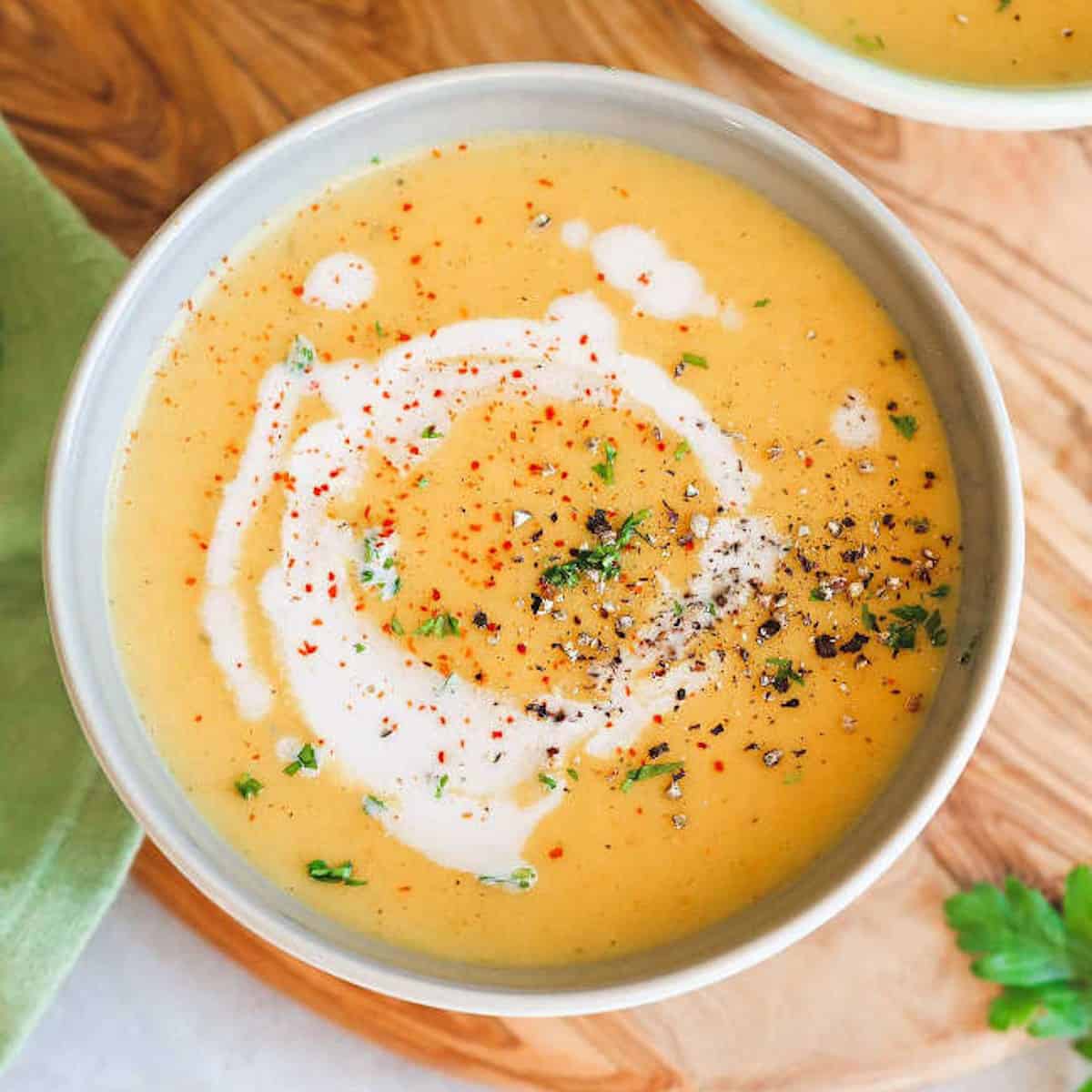 Vegan potato soup with non dairy garnish in a white bowl on a wooden board..