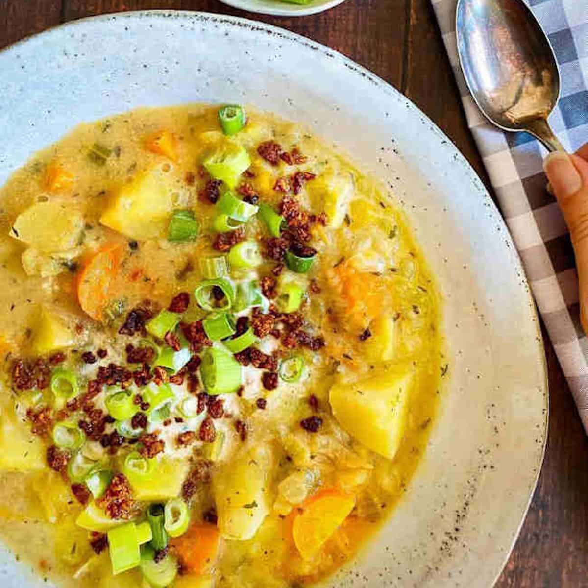 A bowl of vegan potato soup garnished with vegan toppings.