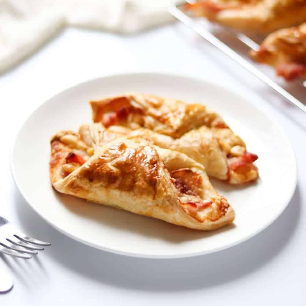 Bacon puff pastry appetizers on a white plate.