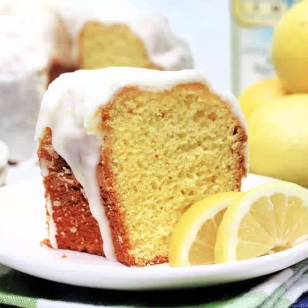 Lemon cake with white frosting and slices of lemon on the side.