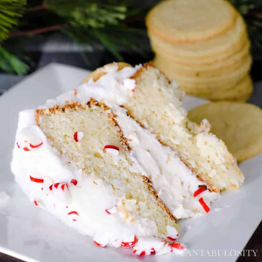 A white cake with white frosting and red sprinkles.