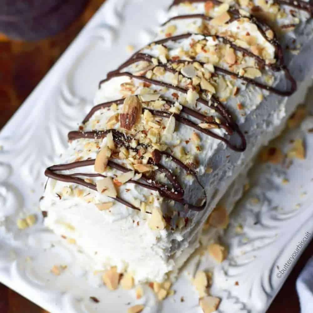 Cake on a white serving plate with chocolate and nut decorations.