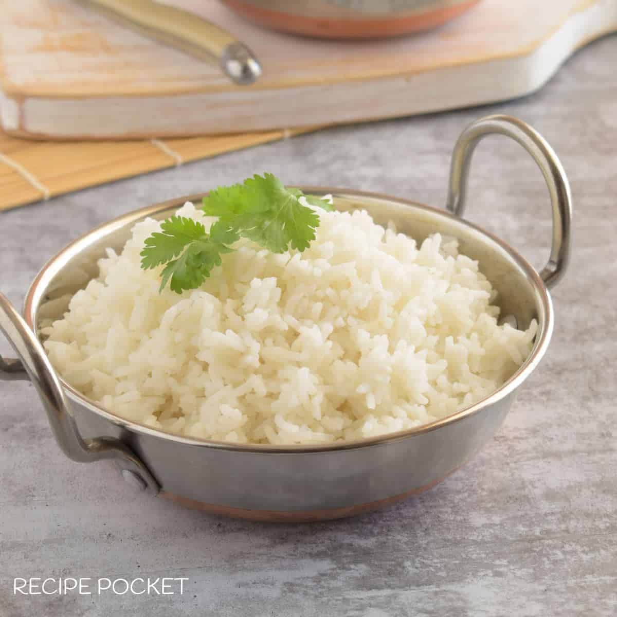 A closeup of cooked basmati rice in a bowl with a white board in the background.