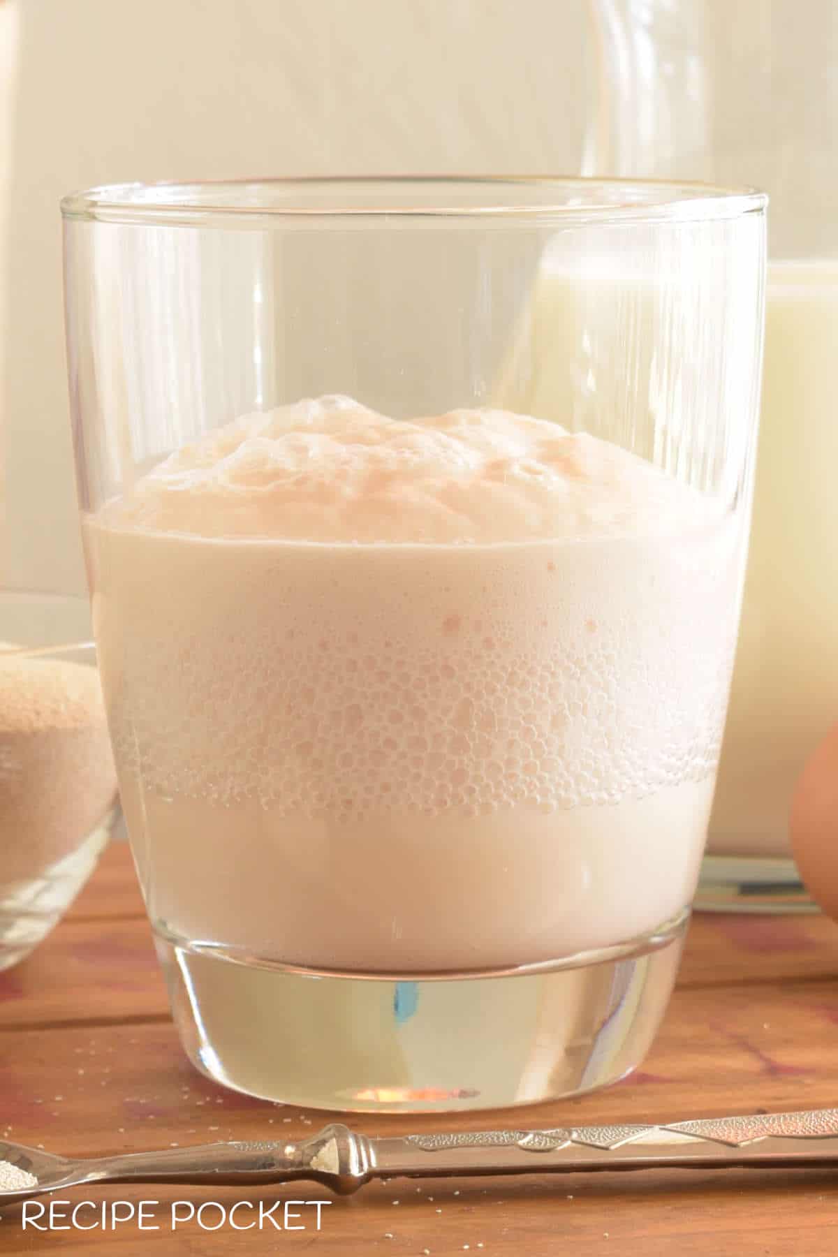 Close up of yeast proofing in a glass with lots of active bubbles.