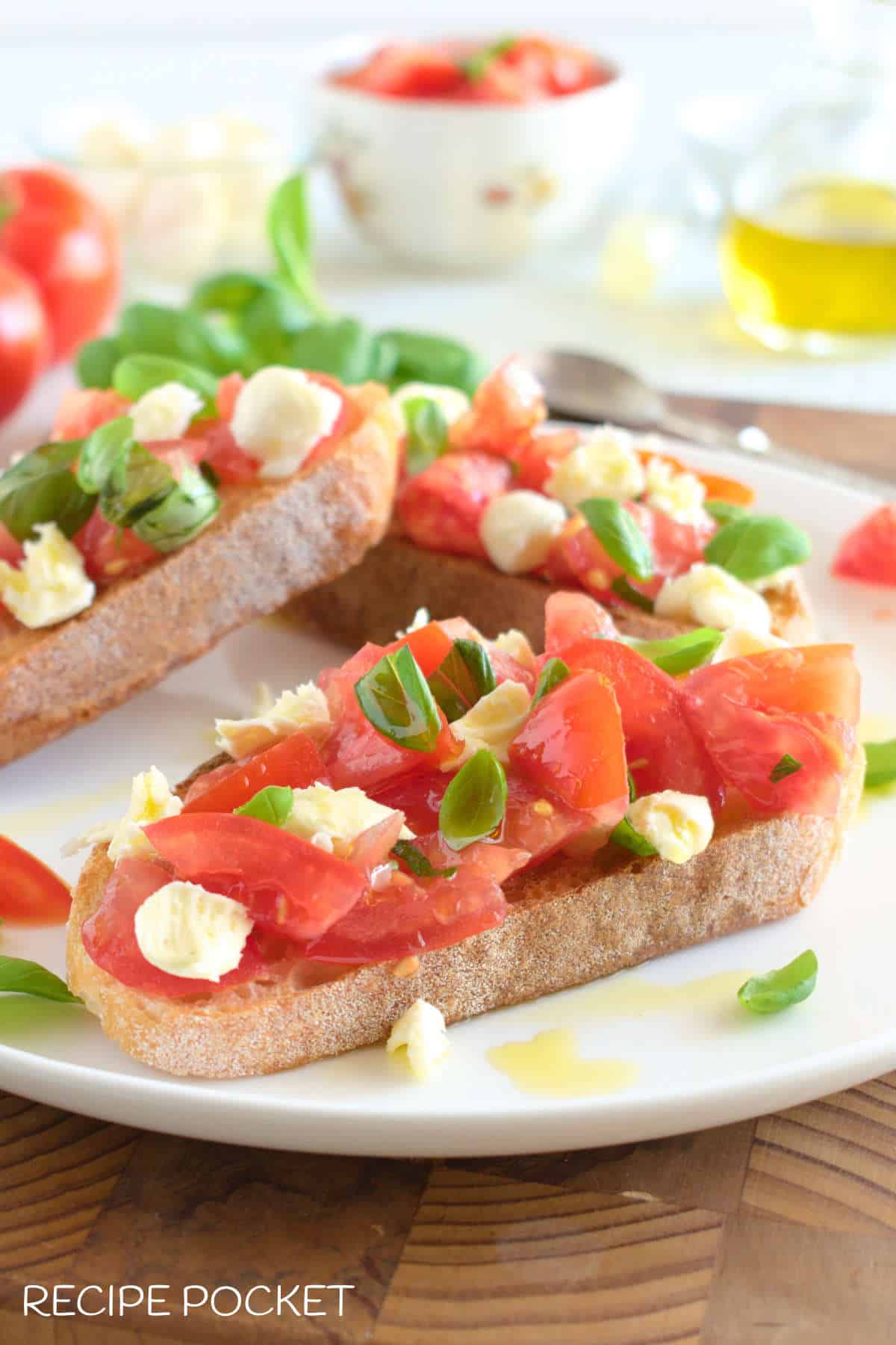 Three bruschetta's with mozzarella and tomato on a white plate.