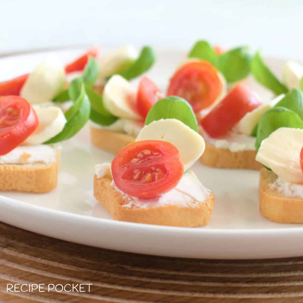Caprese crostini on a white serving plate.