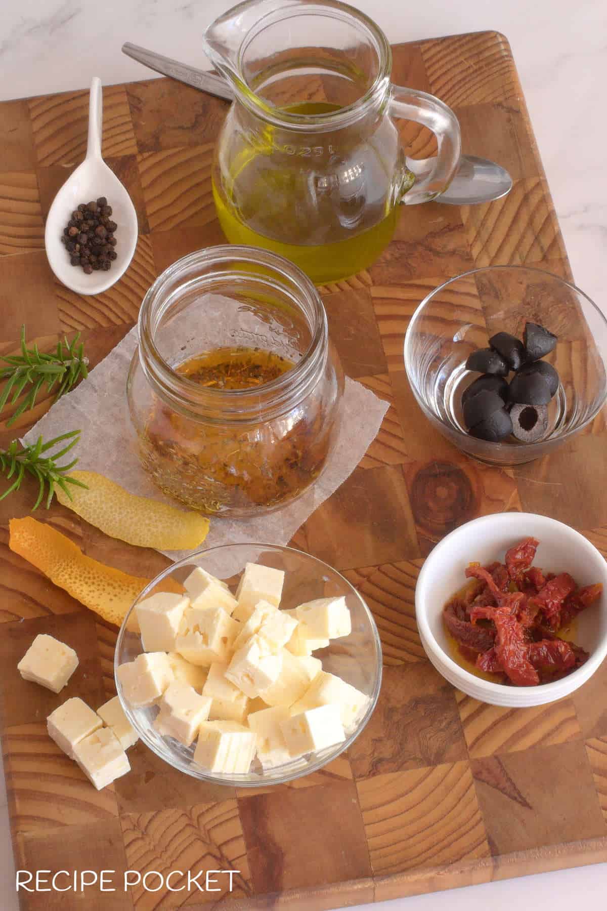 Prepared ingredients for feta in oil on a wooden board.