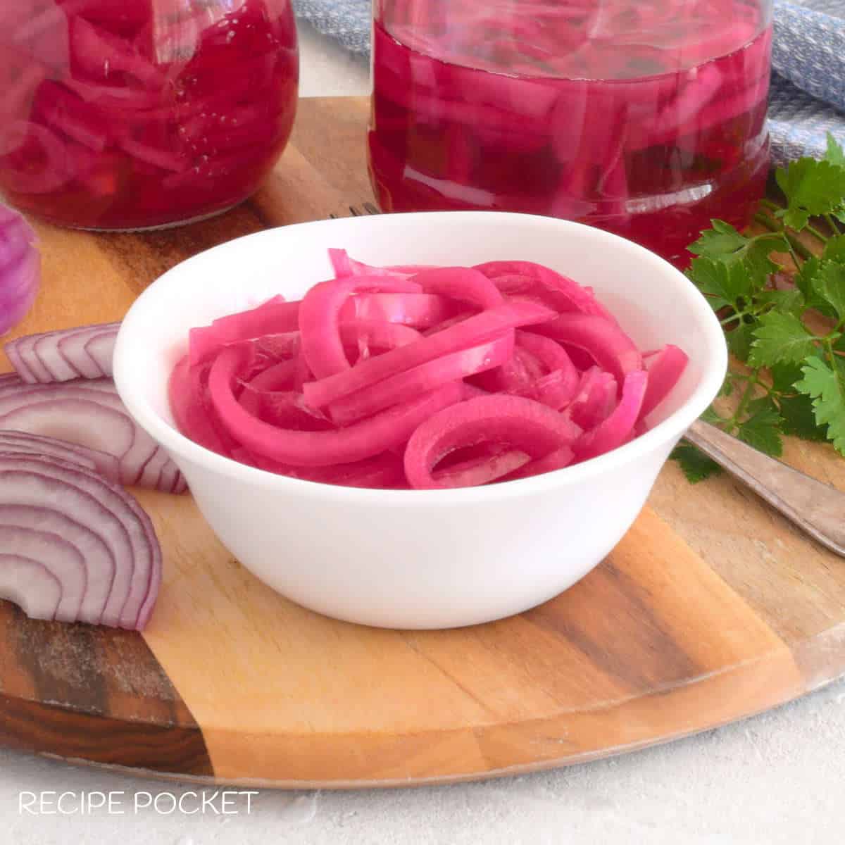 Onion pickles in a bowl on a wooden board.