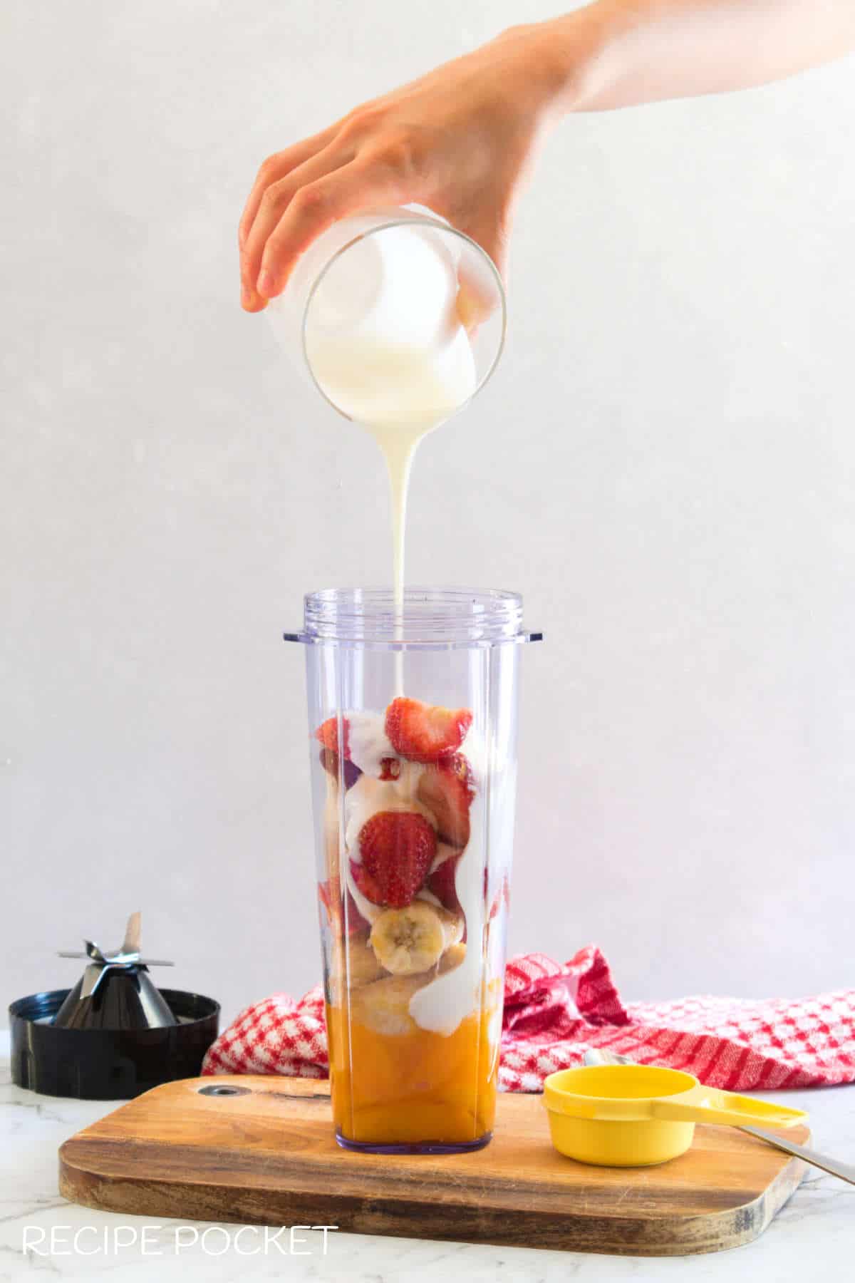 Yogurt being poured over fruit in a blender just.