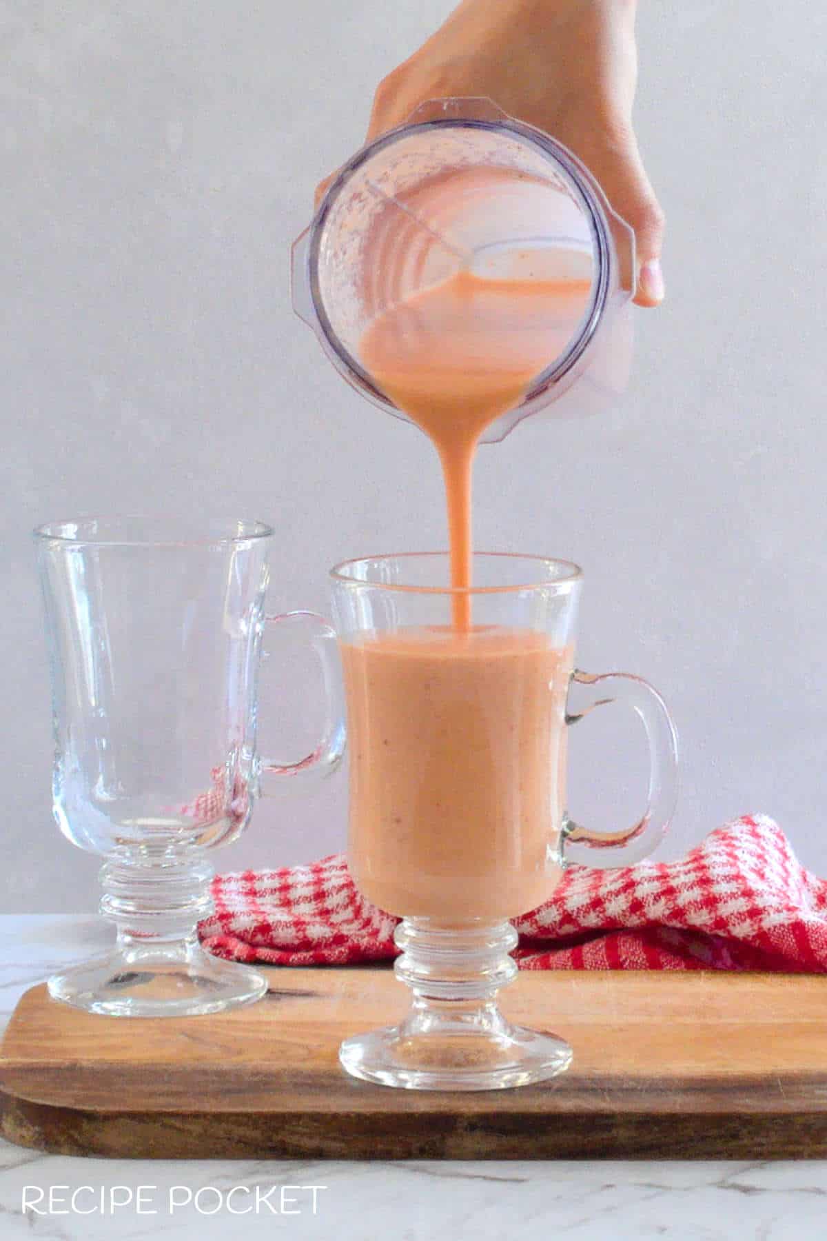 Blended smoothie being poured into a serving glass.