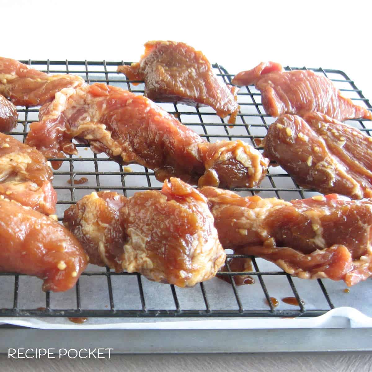 Uncooked marinated pork pieces on a baking tray.