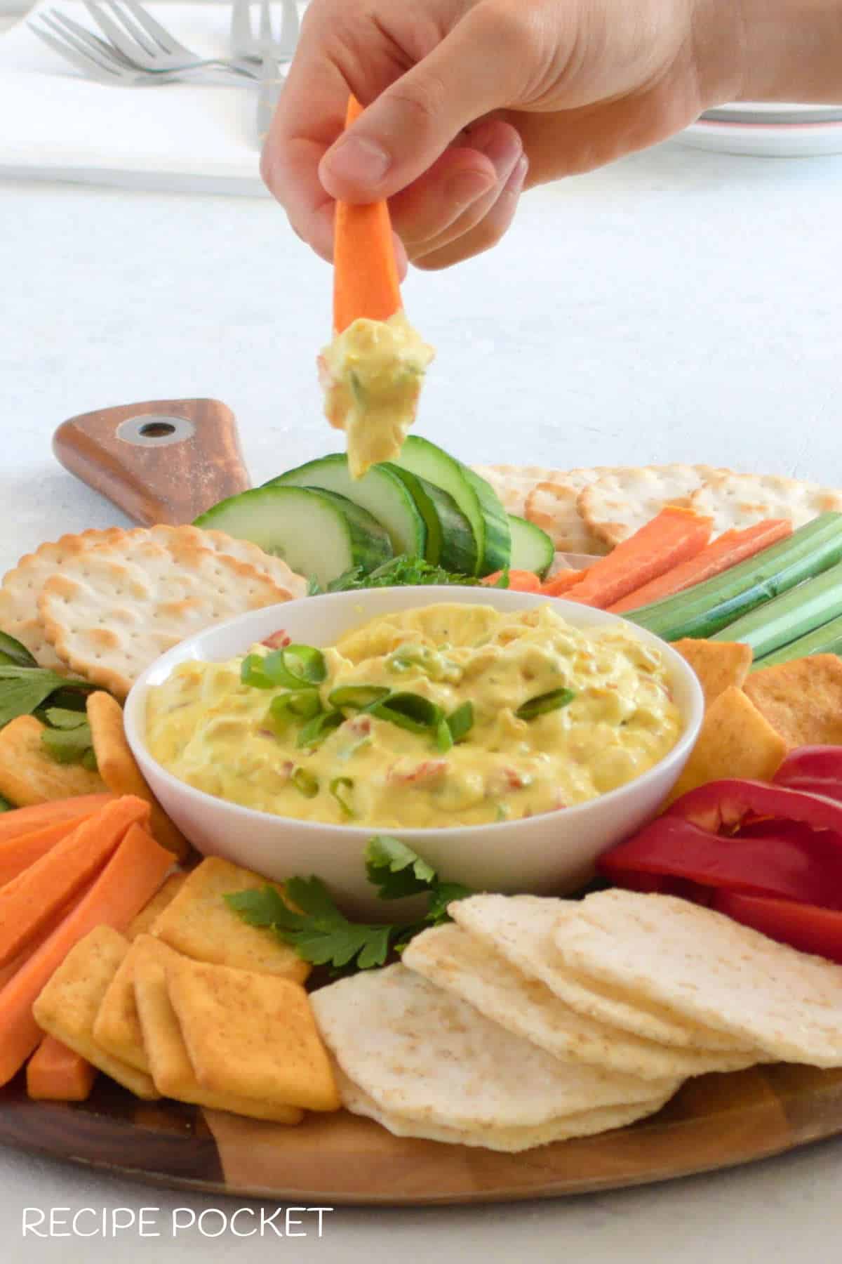 Hand holding a carrot stick with dip on it.