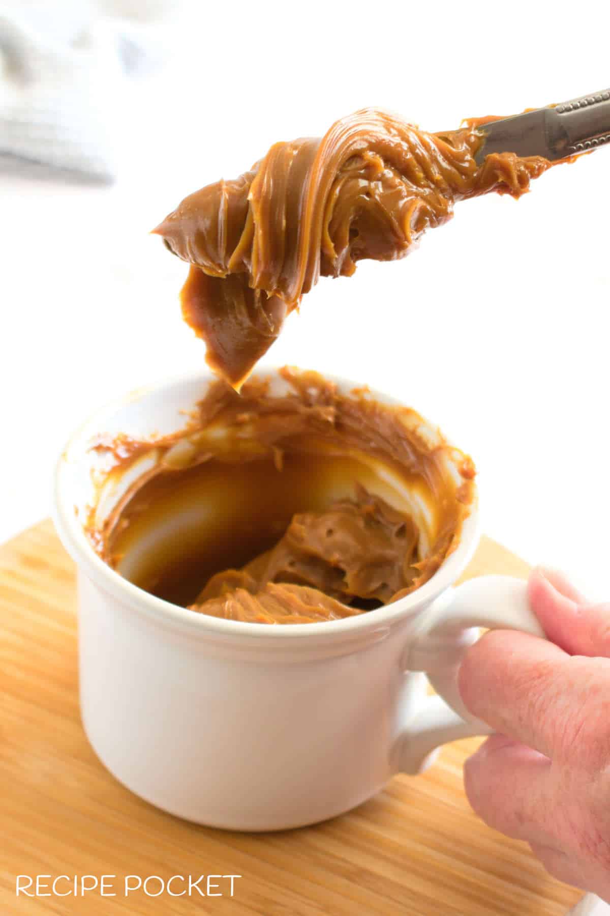 A knife with caramel sauce on it.