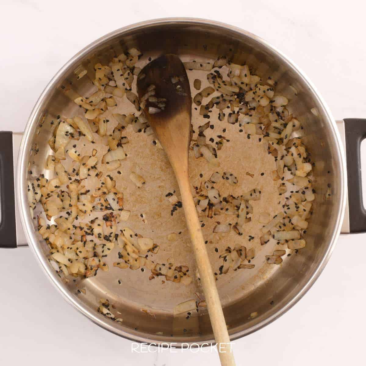 Fried onion and cumin seeds in a pot.