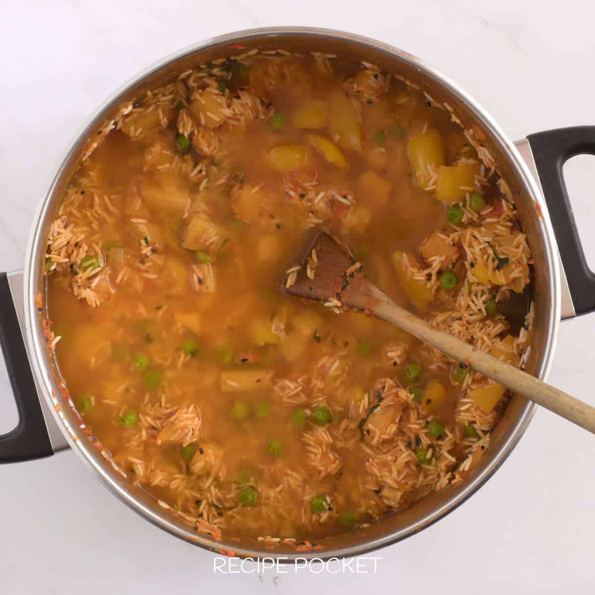 Water in a pot with uncooked rice and vegetables.