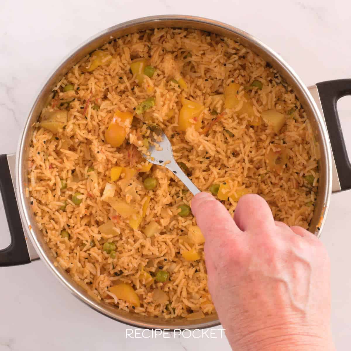Cooked rice being fluffed with a fork.