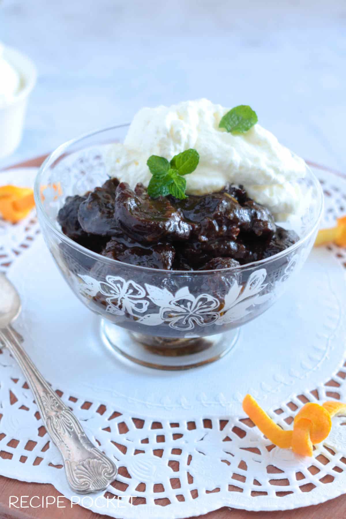 Stewed prunes served as a dessert in a glass bowl with cream.