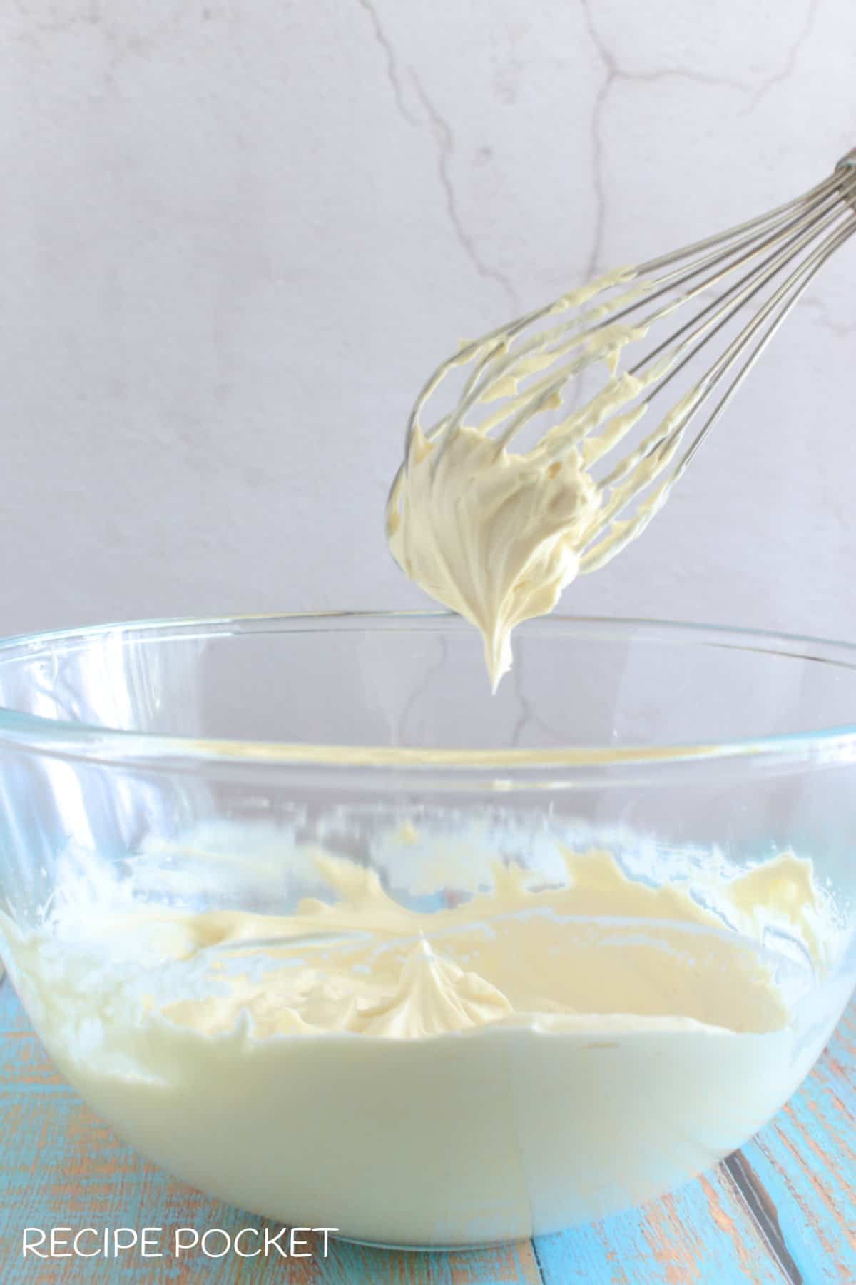 Whipped cream in a bowl and on a whisk.