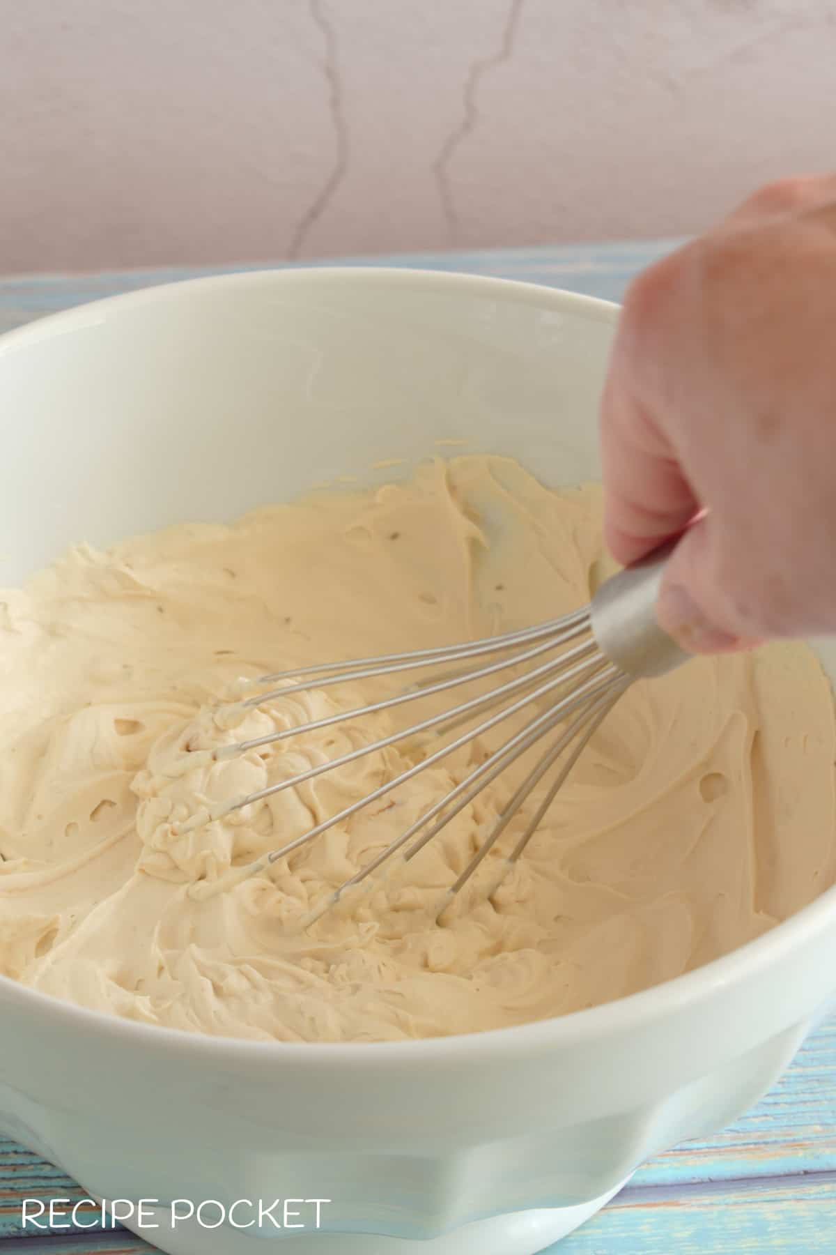 Cream being hand beaten in a bowl.
