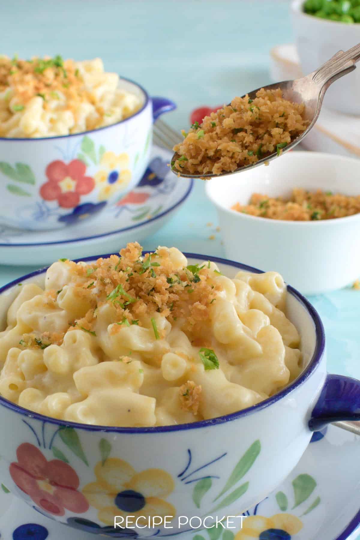 Breadcrumb and parsley topping being spooned on top of pasta.