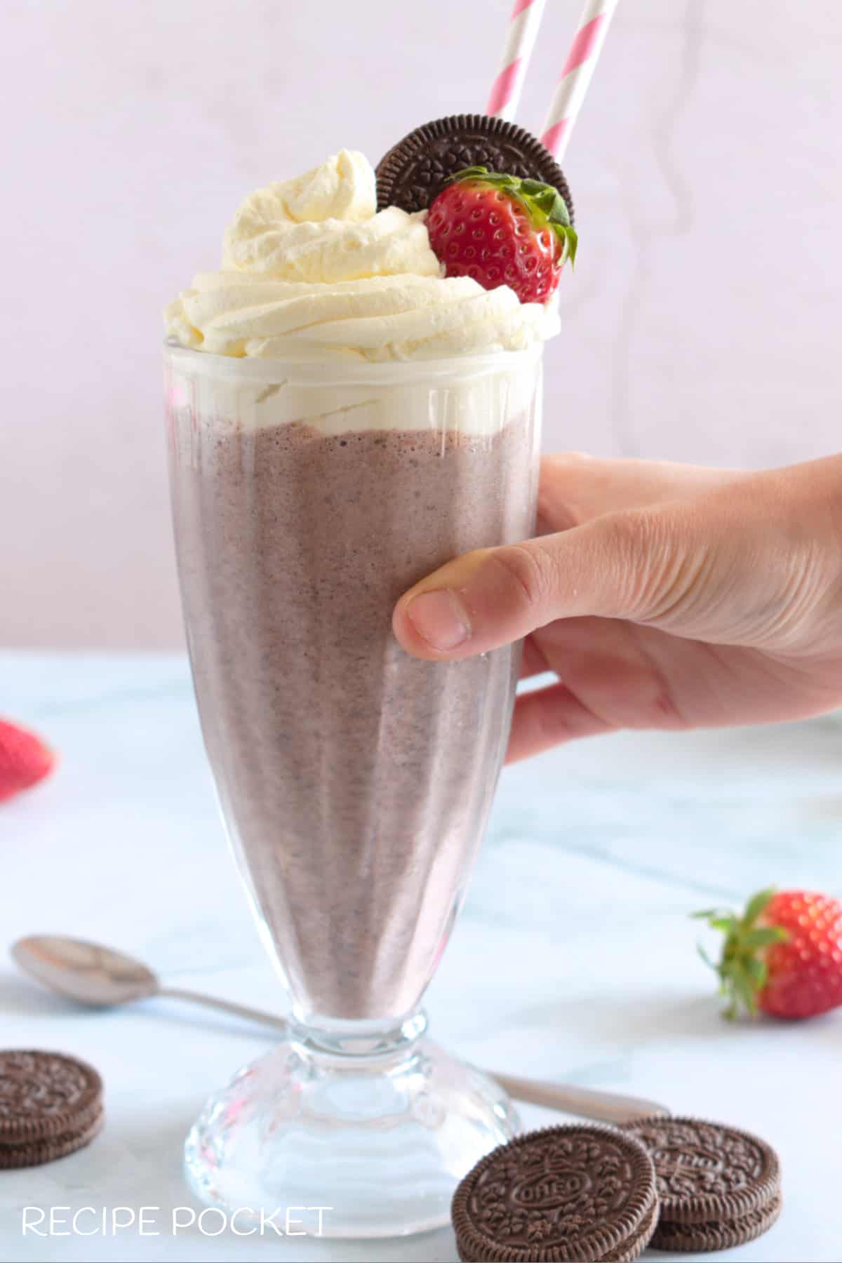A hand picking up a milkshake.