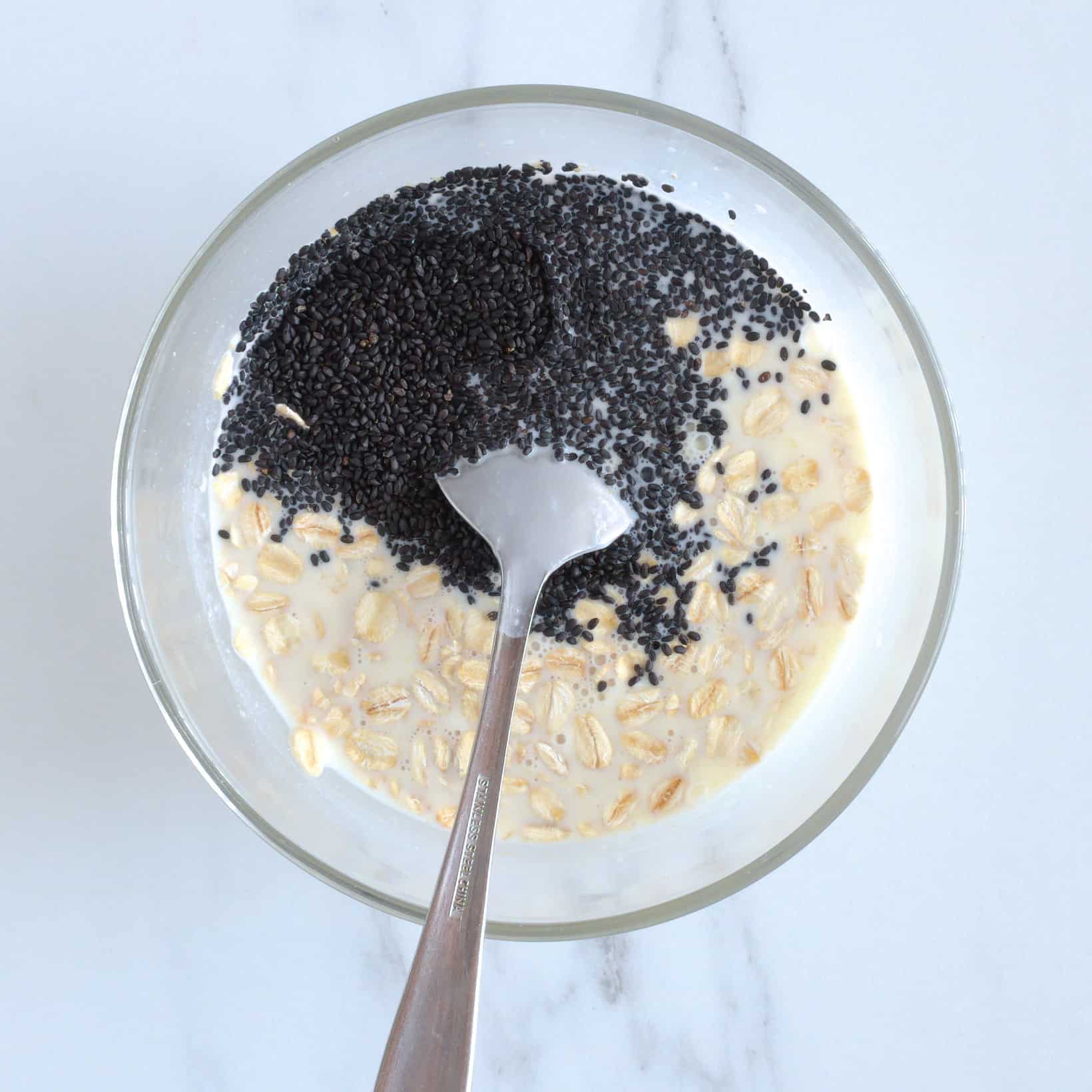 Oats and basil seeds in a bowl with milk and yogurt.