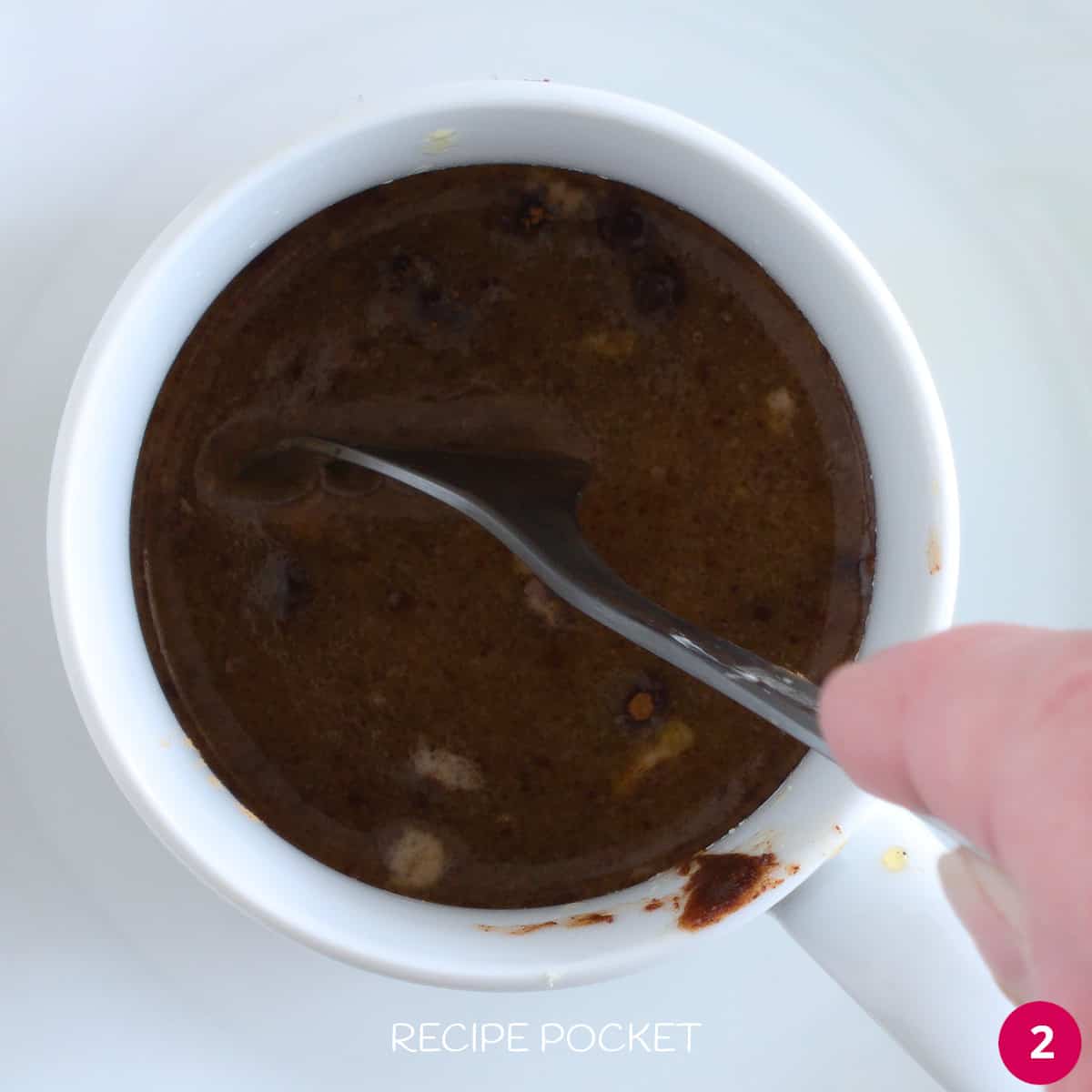 Sugar and spices mixed with melted butter in a mug.