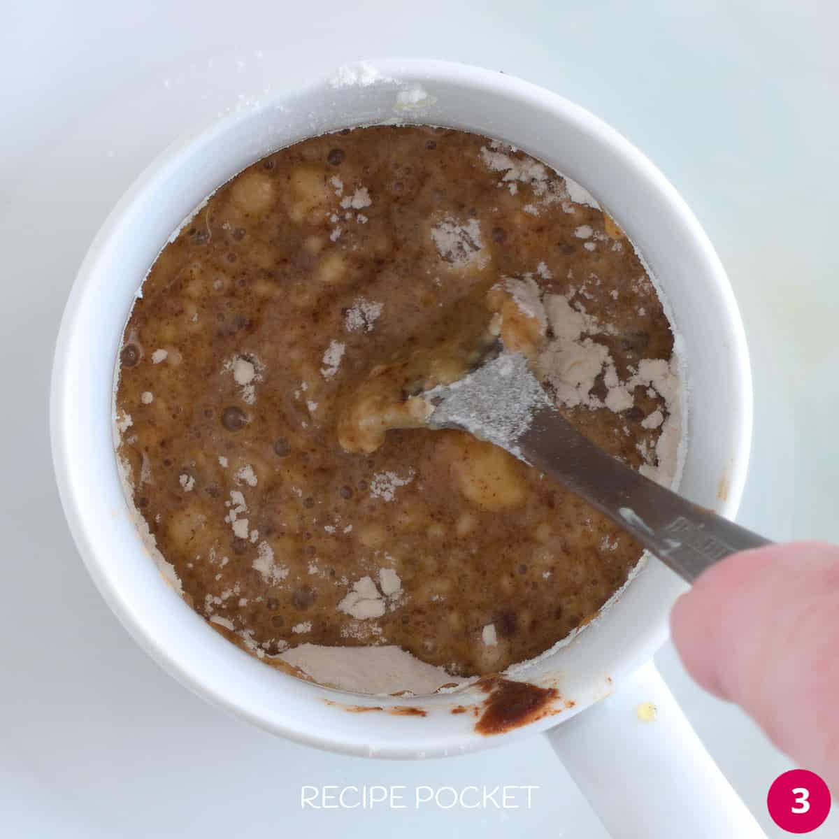 Flour being mixed into butter and spice mixture in a mug.